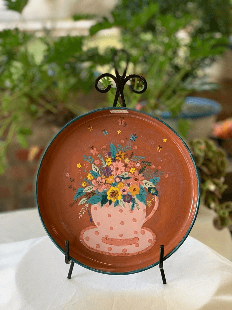 Hand-painted terracotta plate with floral bouquet in a teacup